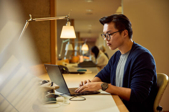 Person working on a laptop in a relaxing space.