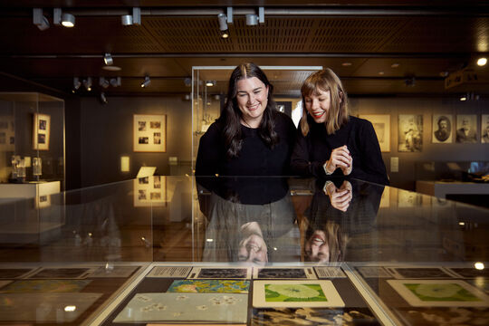 Two people standing together, viewing items inside a display cabinet.