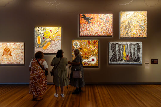 Three women viewing artwork at The unbroken spirit of the Kalkadoons exhibition, State Library of Queensland.