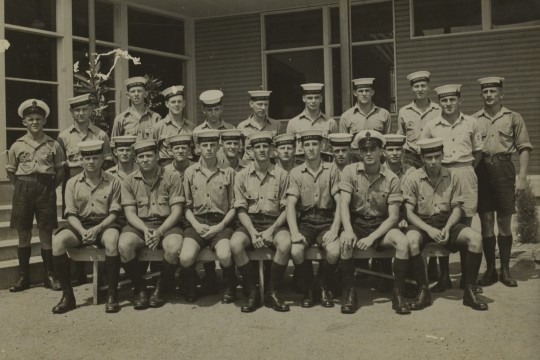 A group of navy recruits in uniform outside a building