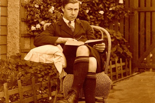 Teenage boy reading a book in the garden 1910-1920