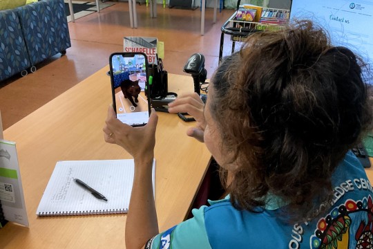A pserson holding a phone showing augmented reality inside a library.