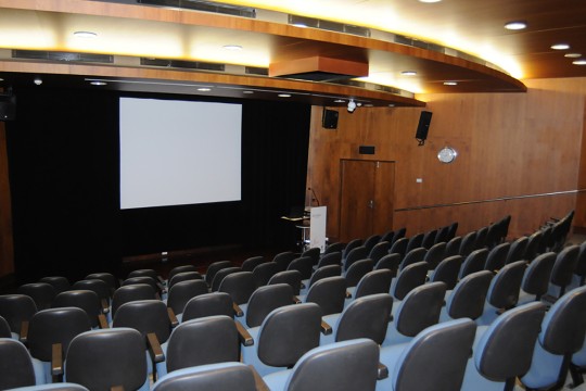 An empty auditorium with large screen and podium at front