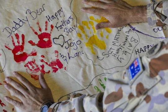Australian soldier looks at artwork produced by soldiers families