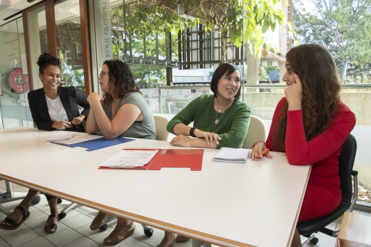 Four Indigenous women are editing at a table
