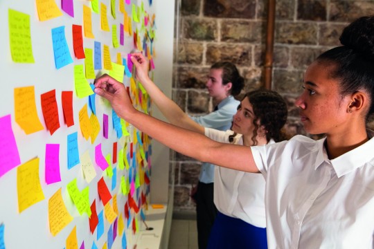 Students adding colourful notes to a whiteboard