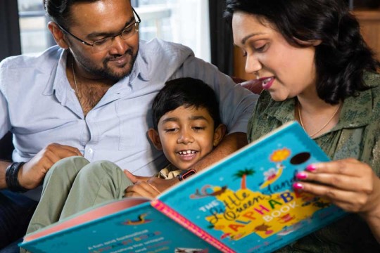 Parents reading book with child