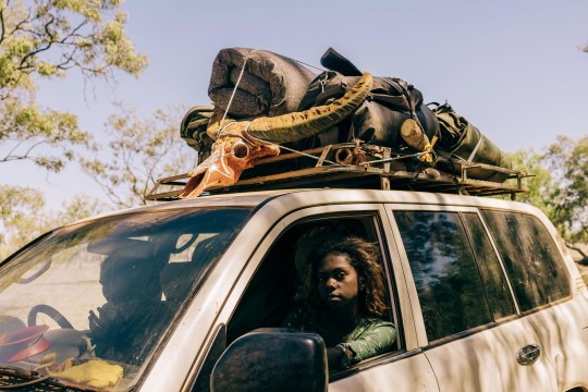 Two people in a car with items stored on the foor.