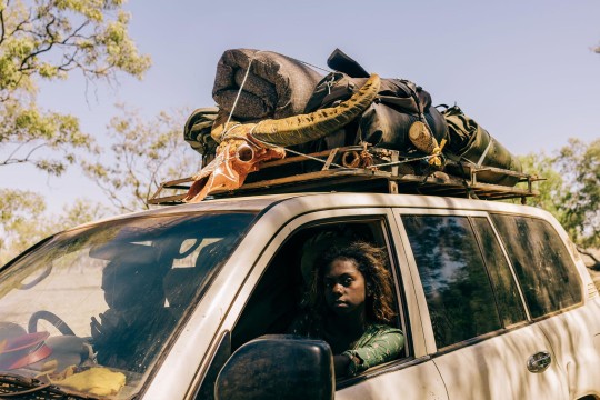 Two people in a car with items stored on the foor.