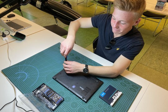 A photo of a person fixing a laptop 