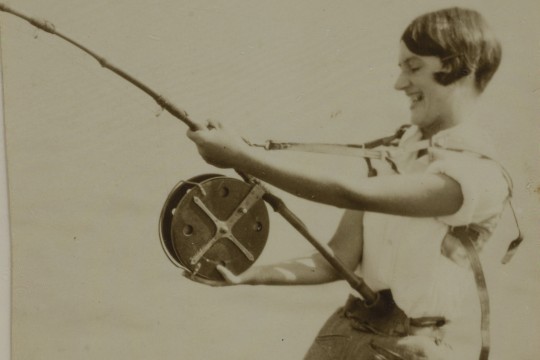 Cora Dunphy trying to reel in a fish at Lindeman Island, 1928.
