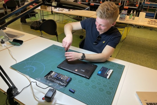 A photo of a man repairing a laptop