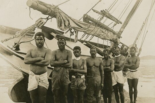 Pearl divers standing in front of their boat in the Torres Strait, 1920