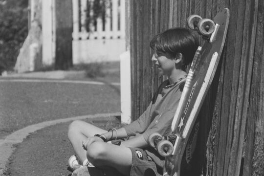 Michael Waldron sitting next to his skateboard, Hynes Street, Fortitude Valley, 1992-1993