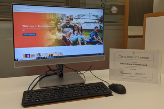 Computer screen displaying home page for FamilySearch with affliate certificate on table on right