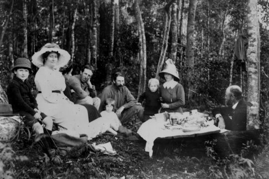 Black and white image of adults and children having picnic in bushland, 1910-1920