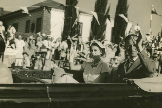 Queen Elizabeth ll and Prince Philip seated in back of car waving to crowds Bundaberg Queensland 1954