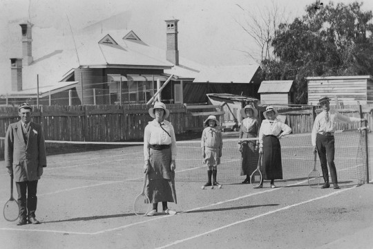 Tennis players standing on a tennis court ca 1915