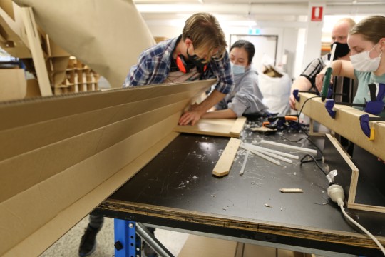 Students folding long pieces of cardboard into beams