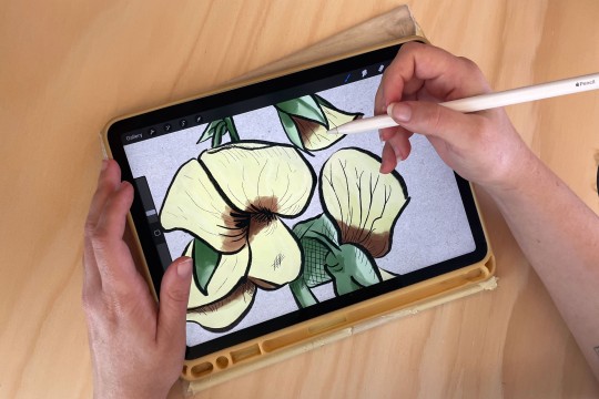 a digital flower drawing on an iPad while a person holds the Apple Pencil