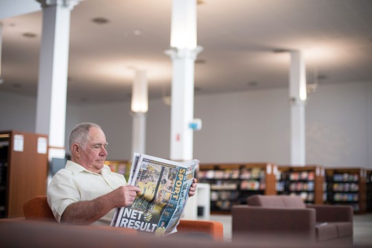 Man reading newspaper in the Caboolture public library.