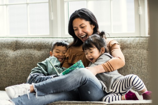 Mother with son and daughter reading on a couch