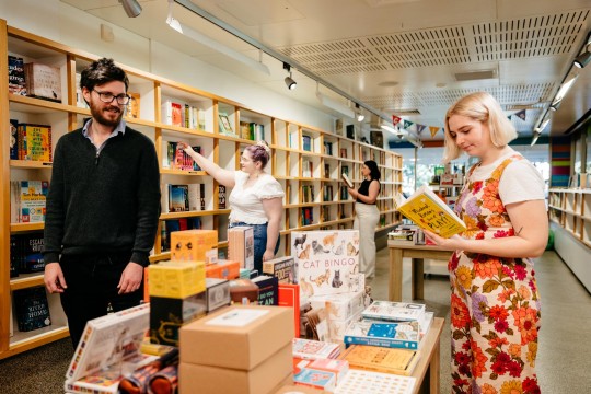 Four visitors perusing books at the Library Shop.