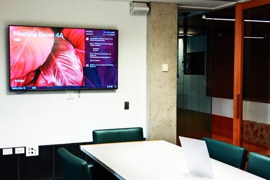An empty meeting room with a colorful flat screen on the wall.