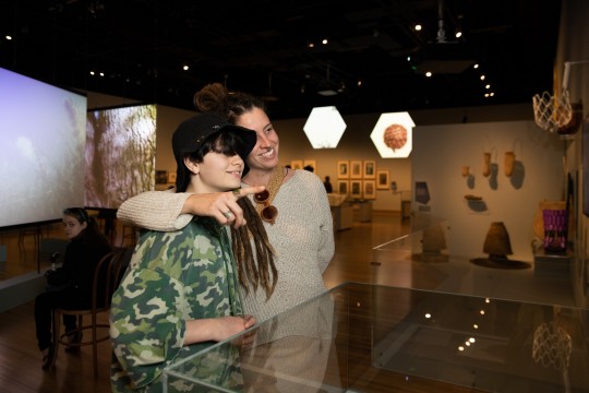 Mother with arm around teenage son at exhibition