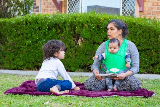 Mother and two children sharing a book outside