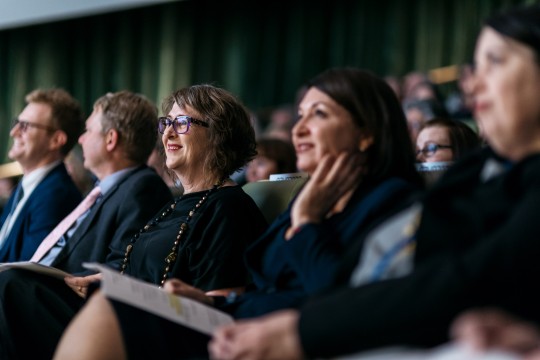 Row of people seated in an auditorium looking upwards.