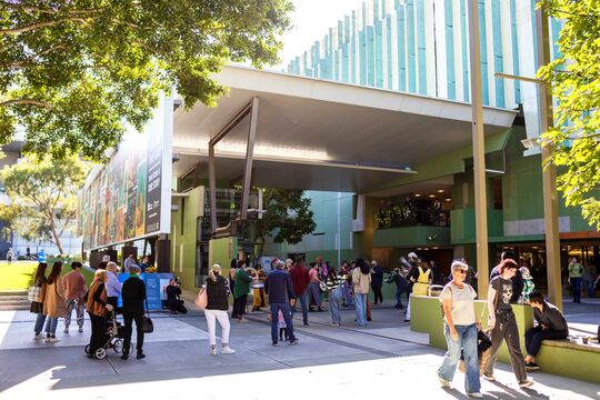Groups of people walking around the front of State Library.