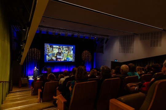 Alexis Wright at the 2023 Queensland Literary Awards. She is onscreen in an auditorium, reading from a speech