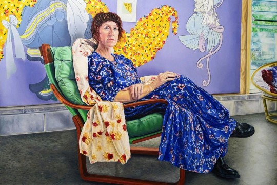Portrait of woman in a dress sitting in a colourful room.