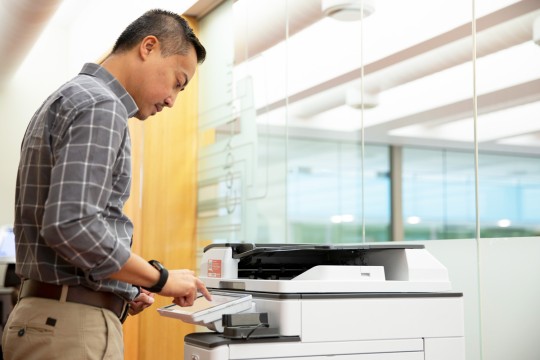 Man standing and using a printer at State Library.