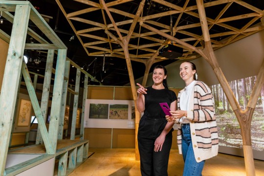 Two smiling people visiting the Purpose Built exhibition.