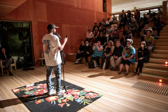 Audience of people watching someone speak into a microphone. 