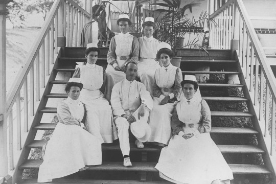 A black and white photograph of six Nurses and one doctor sitting on the steps at the Royal Brisbane Hospital 