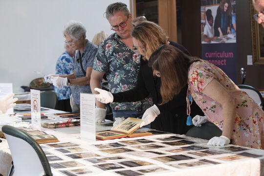 A group of people are studying historical collections on a table