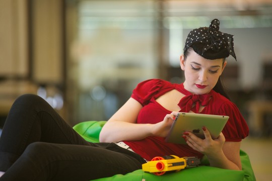 A young woman lounges and views content on her iPad