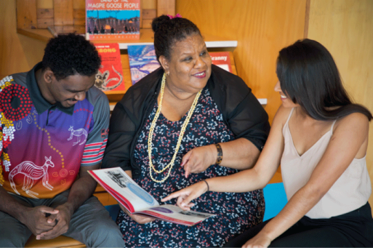 People discussing a book in kuril dhagun at the State Library of Queensland.