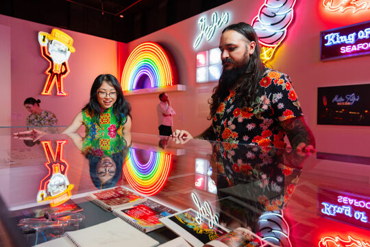 Two visitors viewing neon signs inside slq Gallery