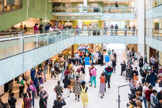 A crowd of people, some playing instruments, on the ground level of State Library. 