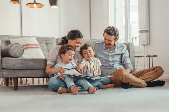 Family reading a book on the floor in living room