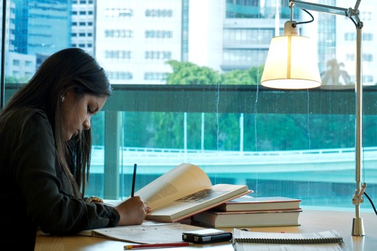A woman with a stack of books paper and pen