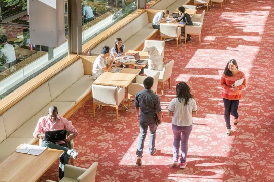 People sitting at desks and walking through the library.