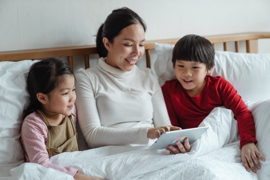 Mother with two young children all looking an ipad