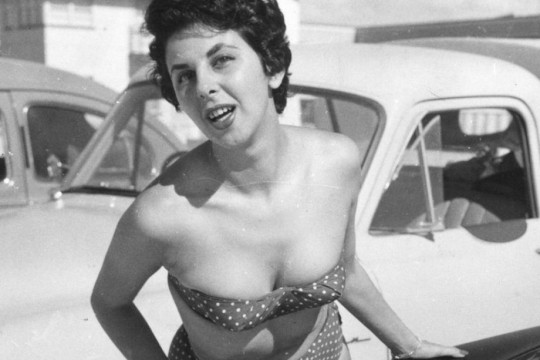Sydney resident Yvonne Amble posing with cars at Surfers Paradise 1958 Photographer unknown John Oxley Library SLQ Negative no 67204