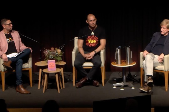 Three panelists sitting in chairs on a stage.