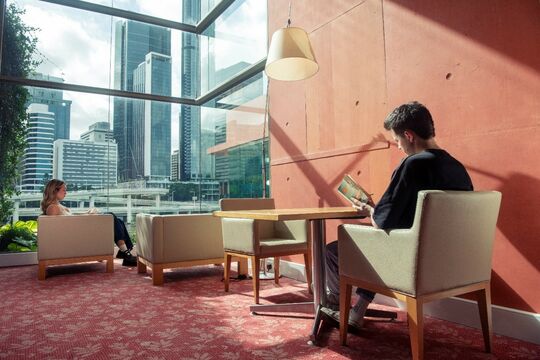 Two people reading in the sunlight at State Library of Queensland
